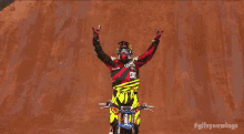 a man riding a dirt bike with his arms in the air ..