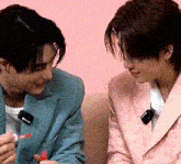 a man in a blue suit and a woman in a pink suit are sitting next to each other on a couch .
