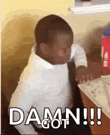 a little boy is sitting at a table with the words `` damn !!! '' written on the screen .