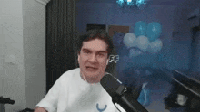 a man wearing headphones is talking into a microphone in a room with balloons in the background .