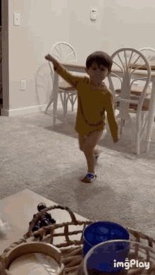 a little boy in a yellow shirt is dancing in a living room with imgplay written on the bottom right