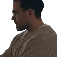a man wearing glasses and a tan sweater looks down