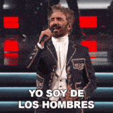 a man in a suit singing into a microphone with yo soy de los hombres below him