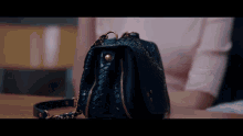 a woman sitting at a table with a black purse on it
