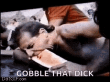 a woman is laying on a table with a knife in her mouth and the words `` gobble that dick '' .