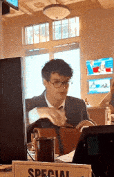a man in a suit and tie is sitting at a table in front of a computer .
