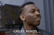 a man is standing in front of a building and saying `` great minds '' .