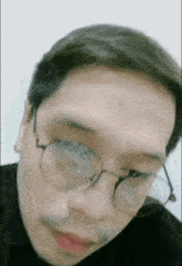 a man wearing glasses and a black shirt looks at the camera .