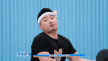 a man wearing a headband and holding a dumbbell has chinese writing on his shirt