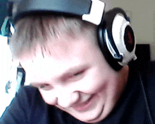 a young boy wearing headphones is smiling and looking down