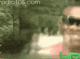 a blurred image of a man wearing sunglasses with radio 105.com written on the bottom