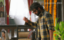 a man in a plaid shirt is standing in a room with the hashtag avantika_0902 on the bottom