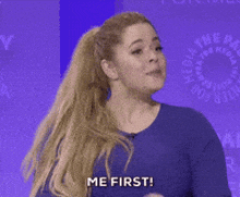 a woman in a blue shirt is giving a thumbs up and says me first