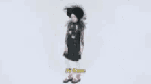 a woman wearing a black hat and a black dress is standing in front of a white background .