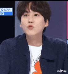 a young man is making a funny face while wearing a blue jacket and a white t-shirt .