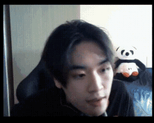 a man is sitting in front of a stuffed panda bear .
