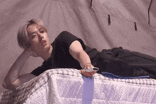 a man laying on a bed holding a remote control