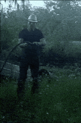 a man in a cowboy hat is holding a hose in his hands