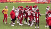 a group of football players are huddled together on a field with a t mobile ad in the background .