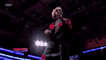 a man is standing in a ring with his arms outstretched in a wrestling ring .