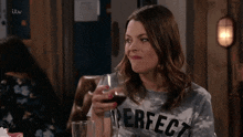 a woman is holding a glass of wine and making a face .