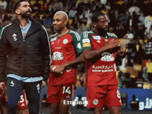 a group of soccer players wearing red shirts with the number 14 on them