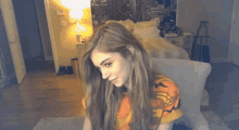 a woman in an orange shirt is sitting on a chair