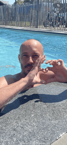 a man making a heart shape with his hands in a pool