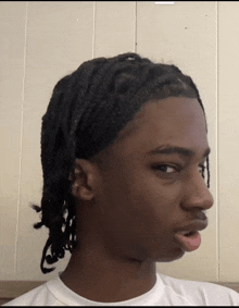 a young man with braids on his head making a face