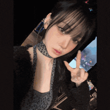 a woman wearing a choker and a leopard print top gives a peace sign