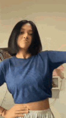 a woman is wearing a blue crop top and white shorts .