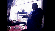 a man sits at a table with a glass of water and an ashtray on it