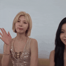 two women are sitting next to each other on a couch and one of them is waving