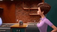 a woman in a purple shirt is standing in a kitchen with a toaster on the counter
