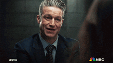 a man in a suit and tie is smiling in a nbc ad