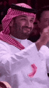 a man with a beard wearing a keffiyeh is clapping his hands
