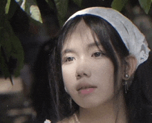 a close up of a woman wearing a white headband and earrings .