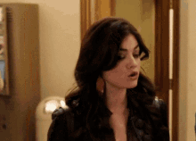 a woman in a leather jacket is standing in a hallway looking at the camera .