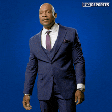 a man in a suit and tie is standing in front of a blue background that says fox deportes on it