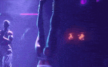 a woman is dancing in a dark room with purple lights .