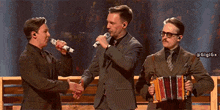 a man in a suit is shaking hands with another man in a suit holding an accordion
