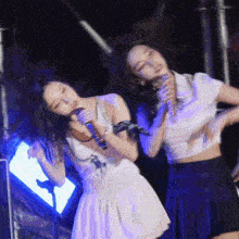 a woman singing into a microphone while another woman looks on