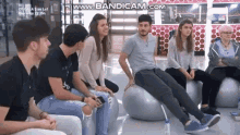a group of people are sitting on exercise balls on a bench .