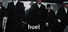 a group of men in suits and hats are walking in a line and the word huel is on the bottom .