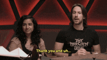 a man and a woman are sitting at a table with the words thank you and uh written on the screen