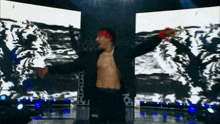 a man without a shirt is dancing on a stage in front of a large screen