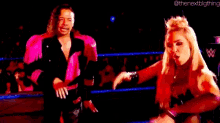 a man and a woman are standing next to each other in a wrestling ring .
