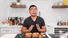 a man in a black shirt is standing in front of a cutting board with slices of food on it