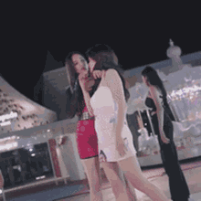 a group of women are standing in front of a building at night