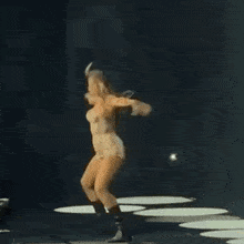 a woman in shorts and boots is dancing on a stage in a dark room .